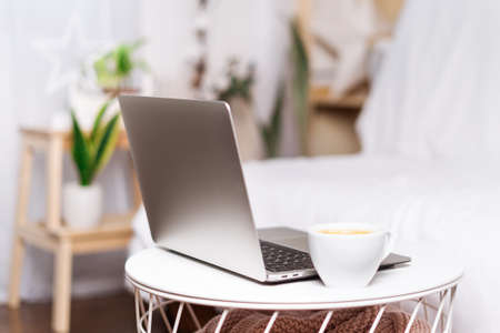 Computer laptop with coffee in white cup at home background. Work remotely or from home. Selected focus. Copy space.の写真素材