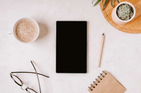 Flat lay mobile smart phone with blank screen of gadget. Digital cell phone with copy space area on white background with pencil, coffee, glasses and stationeryの写真素材