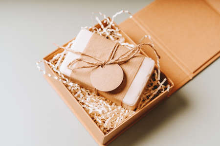 Soap in Craft eco Gift box or present box with bow on gray background with mockup label tag. Copy...