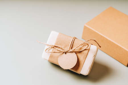 Soap in Craft eco Gift box or present box with bow on gray background with mockup label tag. Copy space for text and design. Package, zero waste, plastic free, eco friendly concept.の写真素材