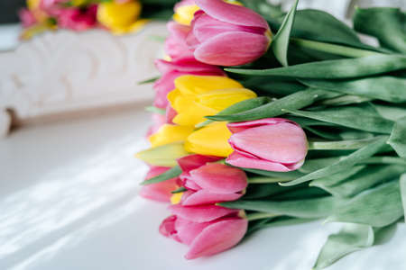 Fresh spring yellow and pink tulips bouquet on white wood table background with copy space for text. Love, easter, International Women day, Mother day and Happy Valentine day conceptの写真素材