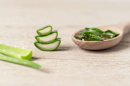 Fresh aloe vera plant, stem slices and gel in glass jar on wooden background, skin therapy, natural organic cosmetic concept.の写真素材