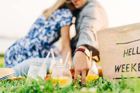 Fresh Homemade Lemonade With lime and lemon On The Grass in sunny park. Blurred green grass and people summer background. Outdoors Picnic, relaxation concept. Hello weekend.の写真素材
