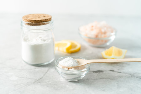 Eco friendly natural cleaners, jar with baking soda, lemon, pink salt and wooden spoon on marble...