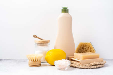 Eco friendly natural cleaners, jar with baking soda, dish brush, lemon, soap on white background. Organic ingredients for homemade cleaning with mockup bottle. Zero waste concept, copy spaceの写真素材
