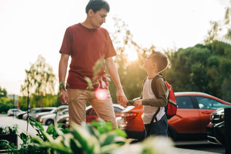 Happy father and kid son going to classes. Parent take child boy to school in first grade. Pupil of...