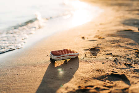 Used old shoe washed up on the shore of a beach, highlighting the worldwide crisis of garbage, plastic pollution. Environment ecology conceptの写真素材