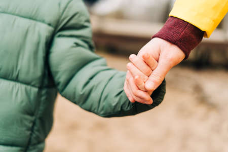 Close up Father and son stand on the shore of the lake and hold hands. Happy family with child kid boy playing and having fun outdoors over autumn park backgroundの写真素材