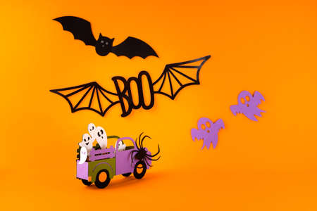 Happy halloween holiday concept. Halloween handmade paper decorations, spiders, ghosts in car, bats, boo text on orange background. Halloween festival party, greeting card mockup with copy space.の写真素材