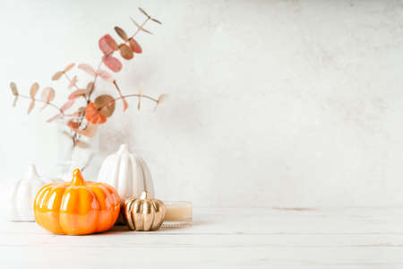 Details of Still life, pumpkins, candle, brunch with leaves on white table background, home decor in a cozy house. Autumn weekend concept. Fallen leaves and home decorationの写真素材