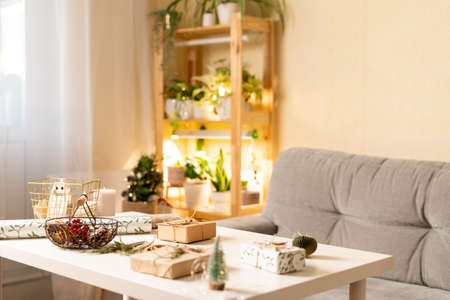 Stylish Christmas room interior with Christmas light and gifts on table, preparing for Christmas holiday. Cozy home. Background with copy space.の写真素材