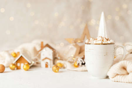Details of Still life, cup of coffee with marshmallows, wooden toy house decor, Christmas lights with sweater on white background, home decor in cozy house. Winter weekend concept with copy spaceの写真素材