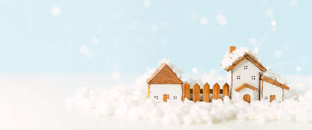 Happy New Year and Merry Christmas banner. Festive blue background with toy wooden house, snow, light bokeh, christmas tree, village and decoration. Copy space for winter holidays greeting card.の写真素材