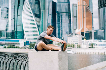 Young fitness man athlete runner stretching legs before exercise run outdoors in city urban street. Healthy lifestyle and sport concept.の写真素材