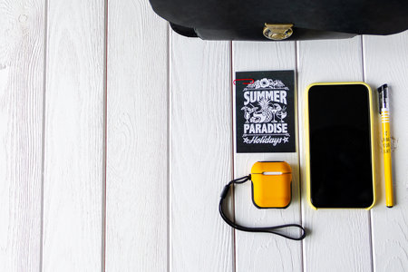Black bag, headphones, smartphone, yellow pen and paper on wooden backgroundの写真素材
