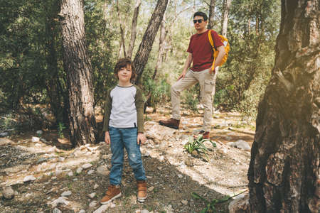 Tourists school boy and his dad walking in the spring forest. Child boy and father wearing casual...