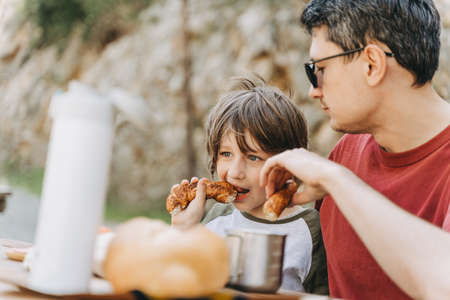 Close-up view of father hugs his school boy son on a family picnic in the mountains. Child kid and...