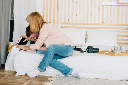 Smiling caucasian school boy kid playing with mom mother on the tablet. Child grandson having fun with his grandmother while playing mobile games on cell phone,の写真素材