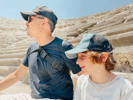 Young father dad and his school boy kid son tourists visiting ancient antique coliseum amphitheater ruins in hot summer day.の写真素材