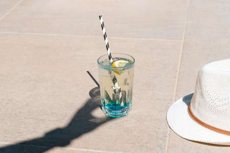 Closeup shot of hands shadow holding sparkling mint lemonade tropical cocktail from the glass standing on the marble floor. Hello summer holiday vacation. Copy blank space.の写真素材