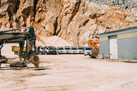 Heavy duty excavator with dump trucks in the background. Quarry mining machinery equipment