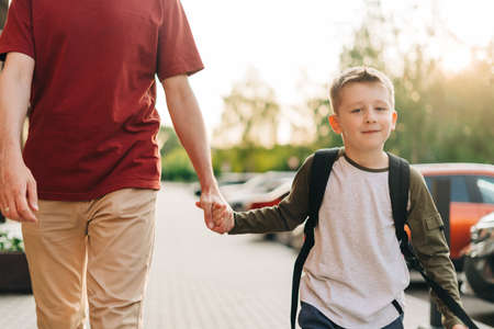 Happy father and kid son going to classes. Parent take child boy to school in first grade. Pupil of...