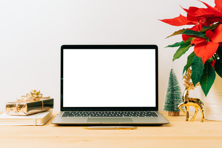 Laptop with mockup blank screen on wooden table with Christmas gift, poinsettia plant flowers on white background. Computer with Mock up and copy space for text.の写真素材