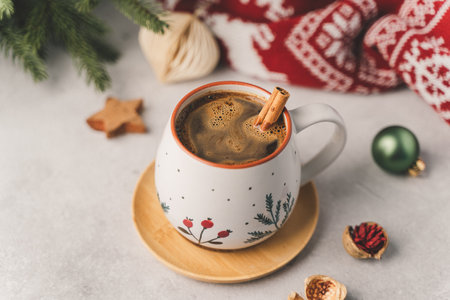 Cup of hot coffee with cinnamon, fir tree, wooden star and warm cozy sweater. Christmas greeting card, lights background. Xmas holiday eco nature decorations. Zero waste concept.の写真素材