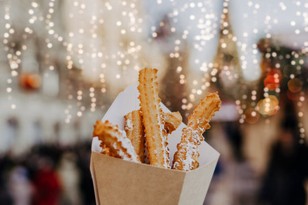 Close up churros on traditional Christmas fair in snow. Enjoying sweets on Xmas market. Winter holidays with family. Merry Christmas.の写真素材