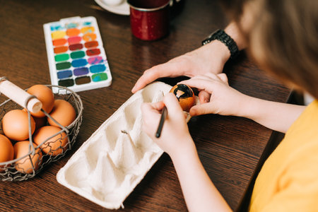 Easter day. Male Father and son painting eggs on wooden background. Family sitting in a kitchen. Preparing for Easter, creative homemade decoration. Child kid boy having fun and painting easter eggsの写真素材