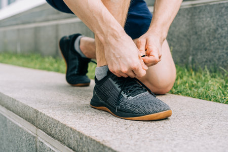 Close up sports man tying shoelace while running outdoors.の写真素材