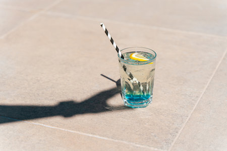 Closeup shot of hands shadow holding sparkling mint lemonade tropical cocktail from the glass standing on the marble floor. Hello summer holiday vacation. Copy blank space.の写真素材