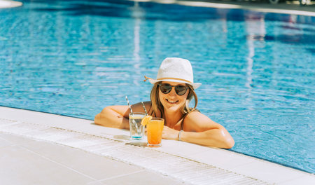 Portrait of beautiful cute smiling young woman lady girl in a bikini, hat, and sunglasses holding...