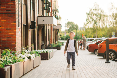 Back to school. Cute child with backpack going to school. Boy pupil with bag. Elementary school student going to classes. Kid walking outdoors on the city street after class.の写真素材