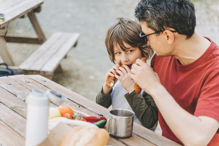 Close-up view of father hugs his school boy son on a family picnic in the mountains. Child kid and his dad taking a rest and enjoying a picnic while hiking in the mountains.の写真素材