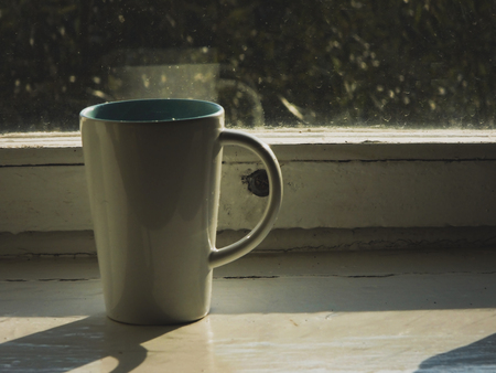 White mug on an old white window sill close-up