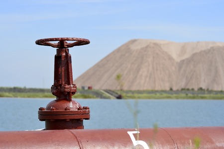 The valve from the pipeline against the background of a salt mine and artificial lakeの写真素材