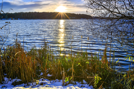 The setting sun on a snowy lake in late autumn.の写真素材