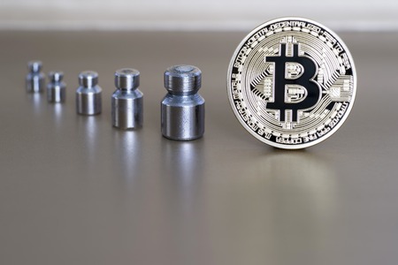 The concept of reducing the cost and rate of cryptocurrency. Bitcoin with weights showing weight,...
