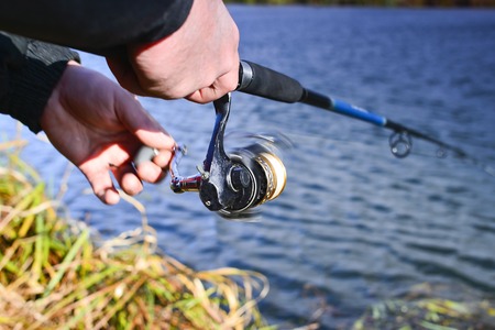A fisherman catches a fish. Spinning reel closeup. Shallow depth of field on the spool of fishing...