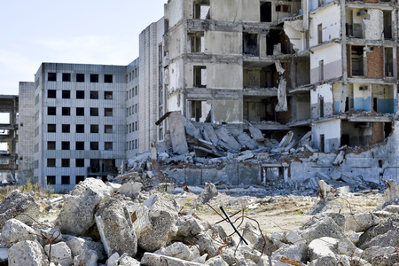 A pile of concrete debris on the background of a large destroyed building. Background. The concept of the consequences of human activities.の写真素材