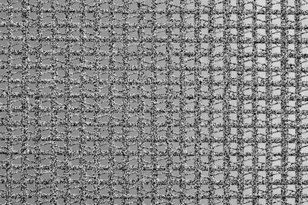 The texture of the background of a synthetic textile in the form of a square lattice.