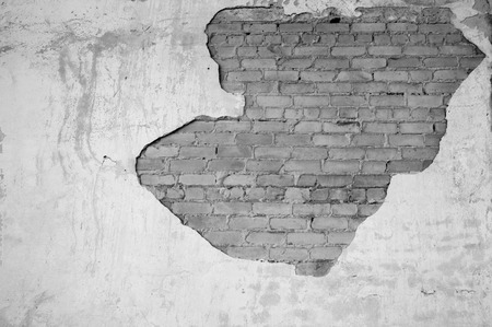 Wall with partially removed plaster in the form of figured drawing of a brick texture. Background. Black and white image.の写真素材