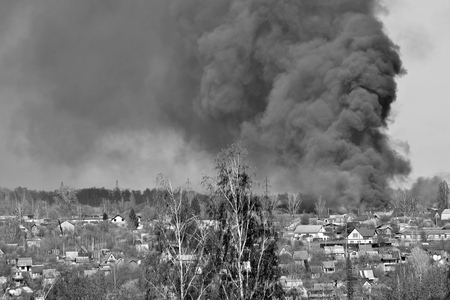 Smoke from a fire on the outskirts of the city in the private sector. Black and white.の写真素材