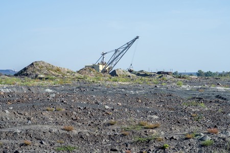A huge excavator carries rock from the unloaded train. The concept of the economy of the third world: mining and environmental problems. Industrial landscape after the destruction of nature by man.の写真素材