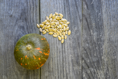 Pumpkin is green-orange and its seeds are stacked in a pile on a wooden vintage rustic backgroundの写真素材