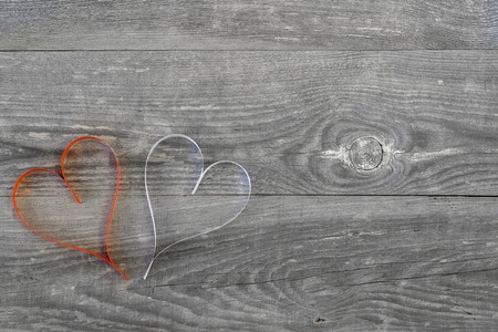 Two hearts of white and red ribbon living coral on wooden vintage background. Romantic card concept. The view from the top. Flat lay.の写真素材