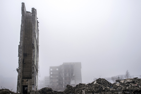 The remains of the wall of a large destroyed building against the background of other destroyed buildings in a foggy haze and a pile of rubble in the foreground. Copy space.の写真素材