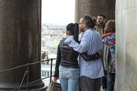 A man and a woman, tourists of European appearance, hugging looking into the distance from the colonnade of St. Isaac's Cathedral in St. Petersburg, Russia, September, 2018. The view from the back.のeditorial素材