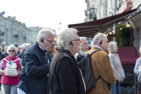 Elderly men of European appearance on a tour in headphones radio guide on Nevsky Prospekt St. Petersburg, Russia, September 2018. Side view.のeditorial素材